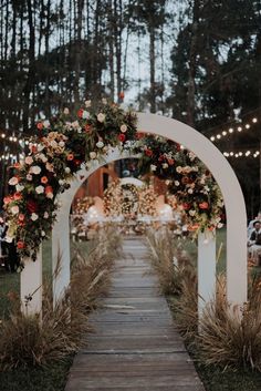 an archway decorated with flowers and greenery is the focal point for this outdoor ceremony