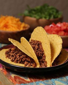 three tortilla chips on a plate with salsa in the bowl and other food