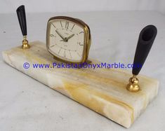 a marble clock sitting on top of a wooden stand next to two black handled candles