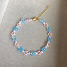 a bracelet with blue, pink and yellow beads is shown on a white tablecloth