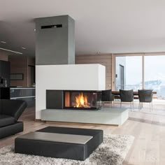 a living room filled with furniture and a fire place next to a dining table on top of a hard wood floor