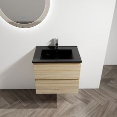 a bathroom vanity with a black counter top and wooden cabinet under a round mirror on the wall