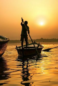 a man standing on top of a boat in the middle of water with a paddle