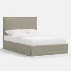 an upholstered bed with white sheets and pillows