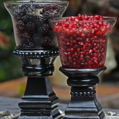 there are two glass vases with berries in them on the same table as each other