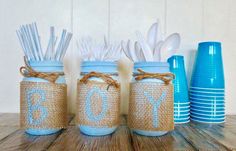 three mason jars filled with blue and white utensils on top of a wooden table