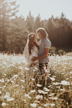 a man and woman standing in the middle of a field full of wildflowers