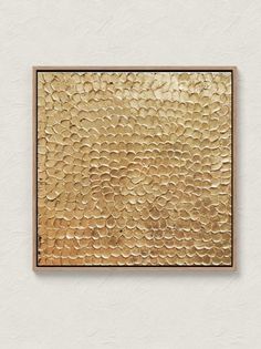 a gold foil textured wall hanging on a white wall with a wooden frame in the middle