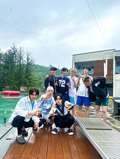 a group of young men standing on top of a wooden deck next to a swimming pool