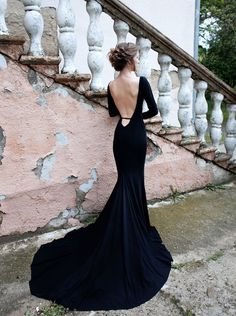 a woman in a black dress is standing on some steps and looking down at the ground