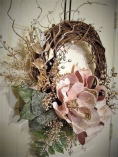 a wreath with flowers and leaves hanging on a door handle in front of a white wall