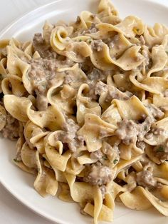 a white plate topped with pasta and meat