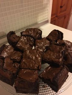 chocolate brownies sitting on top of a glass plate in front of a white tile wall