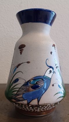 a blue and white vase with a bird painted on it's side sitting on a table