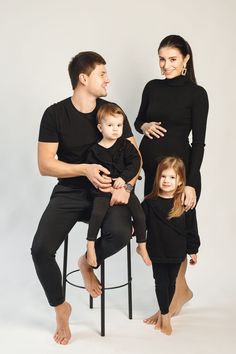 a man, woman and child sitting on a stool in front of a white background