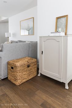 a living room with a gray couch and white cabinet next to a brown wooden floor