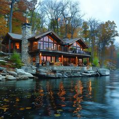 a large house sitting on top of a lake next to a forest filled with trees