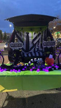 a green table with purple flowers and decorations on it in front of a truck that says beetlejuice