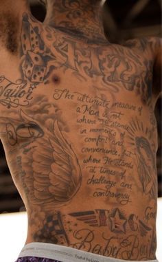 the back of a man with tattoos on his arms and chest is covered in writing