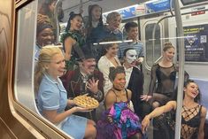 a group of people sitting on a subway car with their mouths open and hands in the air