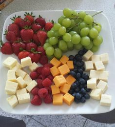 grapes, strawberries, and cheese are arranged on a platter for a snack