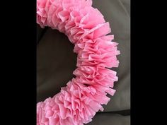 a pink ruffled wreath sitting on top of a couch next to a black pillow