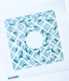 a blue and white square with green leaves on the inside is surrounded by snowflakes