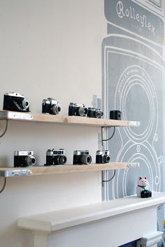 some shelves with cameras on them in front of a wall