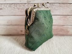 a small green purse sitting on top of a white table next to a wooden wall