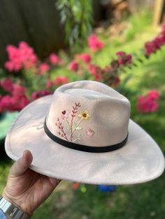 Hand embroidered felt mixed polyester wide brim hats with 2 color options which are cream and black. They are one size and have adjustable ribbons in it. Cream has leather and chain belt around it. Black has a leather ribbon around it. Note: Embroidery is stitched only on the right side of the hat. It doesn't fully wrap around the crown. Cream hat size crown is 7 inches, total with brim 15 inches. Black hat size crown is 7 inches, total with brim 13 inches. Do not wash. Spot clean if needed. Trendy Brimmed Felt Hat For Country Events, Trendy Curved Brim Felt Hat For Festivals, Trendy Wide Brim Felt Hat For Festivals, Spring Adjustable Fedora Felt Hat, Adjustable Fedora Felt Hat For Spring, Spring Fedora Felt Hat With Adjustable Fit, Adjustable Short Brim Felt Hat For Spring, Trendy Short Brim Felt Hat For Festivals, Country Style Felt Hat For Beach In Spring