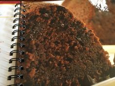 a close up of a piece of cake on a plate with a spiral notebook in front of it