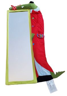 a red and green frog sleeping bag next to a mirror