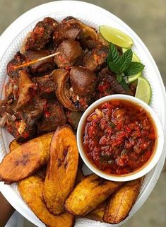 a white plate topped with meat and veggies next to a bowl of sauce