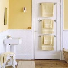 a bathroom with yellow walls and towels hanging on the door