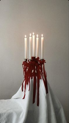 a group of white candles sitting on top of a table next to each other with red ribbons