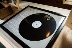 a black and white record on display in a wooden frame with writing underneath it,