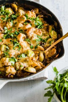 a skillet filled with chicken, artichokes and sauce on top of a white table