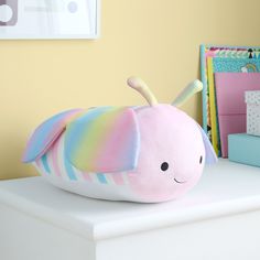 a colorful stuffed animal sitting on top of a white table next to a pile of books