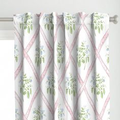 the curtains are decorated with flowers and green leaves on white fabric, hanging in front of a window