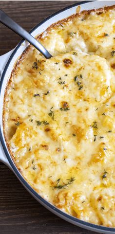 a casserole dish with cheese and herbs in it, on a wooden table