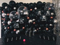 black and silver balloons are stacked on top of each other in front of a backdrop