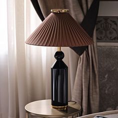 a lamp that is sitting on top of a table next to a window with drapes