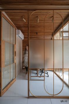 an office with wooden walls and glass partitions in the center, while a person walks by