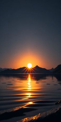 the sun is setting over water with mountains in the background