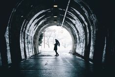 a person holding an umbrella walking through a tunnel