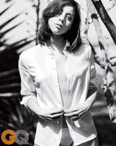 a woman standing in front of a tree with her hands on her hips and looking at the camera