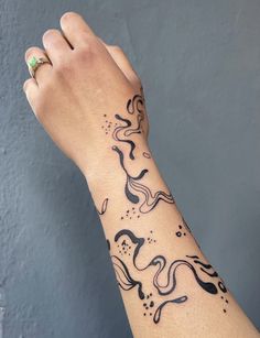 a woman's arm with a black and white tattoo design on the left wrist