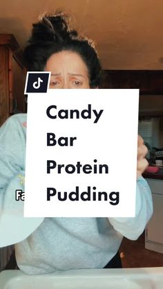 a woman holding up a sign with the words candy bar protein pudding written on it