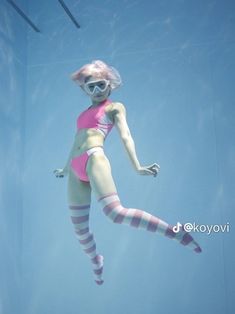 a woman in pink swimsuit and striped socks diving under water with her feet up