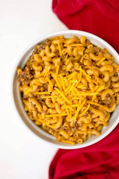 a white bowl filled with macaroni and cheese on top of a red cloth